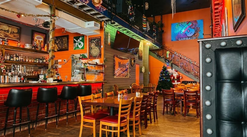 Vibrant Mexican restaurant interior with a bar, dining tables, and festive holiday decorations.