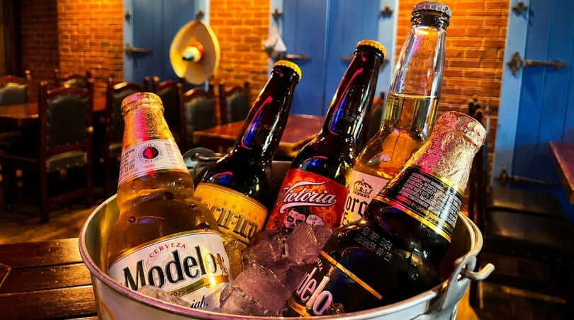 Bucket of assorted Mexican beers on ice, including Modelo, Victoria, and Pacifico, in a restaurant.